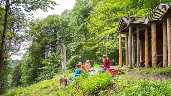 A group of people sitting in the woodland at Allen Banks and Staward Gorge outside a wooden structure